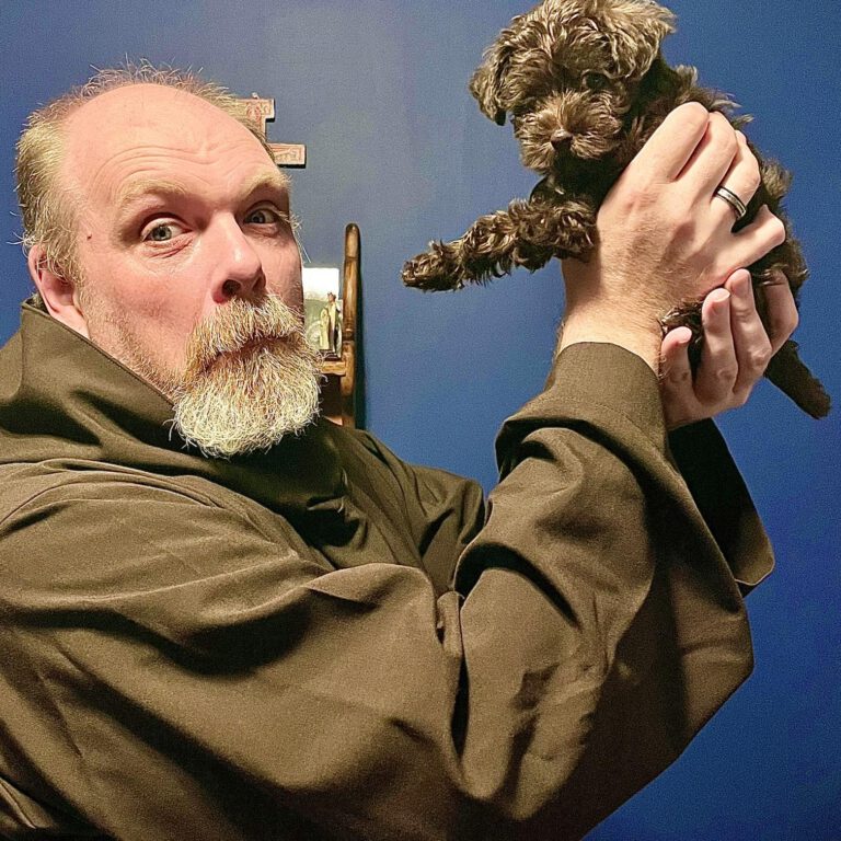 Photo showing our bishop Peter lifting up a puppy.